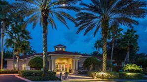 A hotel entrance with a red door, palm trees, and a well-lit driveway. - Luxury Lake View 3 bedroom in resort community. Disney 3 miles (Kissimmee)