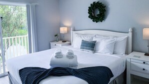 A bedroom with a bed, nightstands, a ceiling fan, a window with curtains, and a view of greenery outside. - Luxury Lake View 3 bedroom in resort community. Disney 3 miles (Kissimmee)