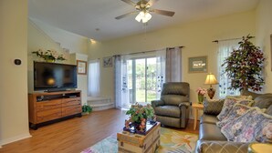 A living room with a television, a sofa, a chair, and a coffee table with a floral rug. - Near Disney & Epic Universe: Home w/ Resort Perks (Kissimmee)