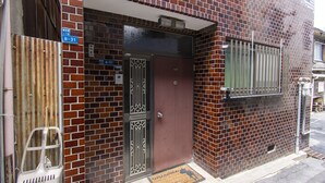 A brick building with a wooden door, a metal gate, and a window with bars. - Ra Villa Hanazono (Osaka)