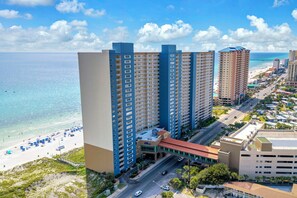 A high-rise hotel with multiple floors, a beach view, and a parking area.