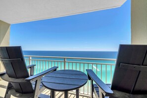 A balcony with a view of the ocean, equipped with a table and two chairs.