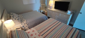 Una habitación de hotel con dos camas, televisión, cómoda y lámpara.