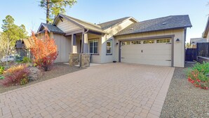 A two-story house with a garage, a brick driveway, and a landscaped front yard with trees and shrubs. - Hot Tub + Fire Pit: Modern Flagstaff Home (Flagstaff)