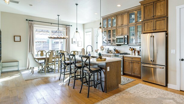 A modern kitchen with wooden cabinets, stainless steel appliances, and a central island with bar stools. - Hot Tub + Fire Pit: Modern Flagstaff Home (Flagstaff)