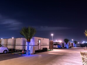 A parking lot with several large white RVs labeled 'TRA+CAN' and a white car parked nearby. - T-PARK Airport Side 1 (Miyakojima)