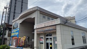 A hostel named "HOSTEL HIROSAKI" with a modern design, located in an urban area with a tall building in the background. - Hostel Hirosaki - Hostel (Hirosaki)