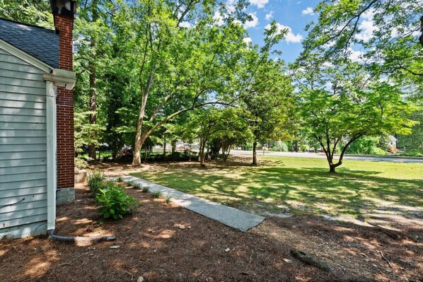 A residential property with a brick house, a paved driveway, and a well-maintained lawn with trees.