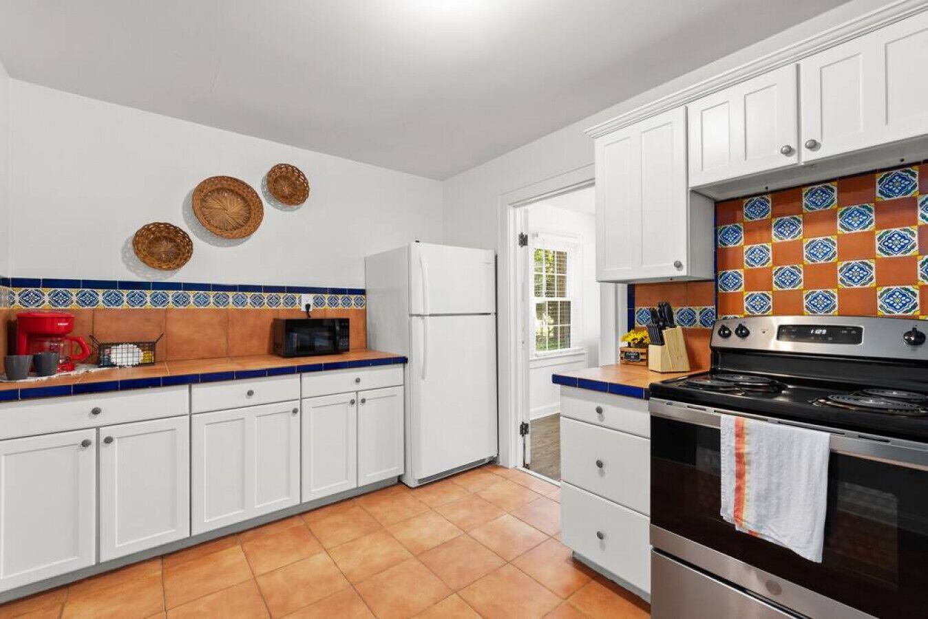 A kitchen with white cabinets, a stainless steel stove, and a microwave.