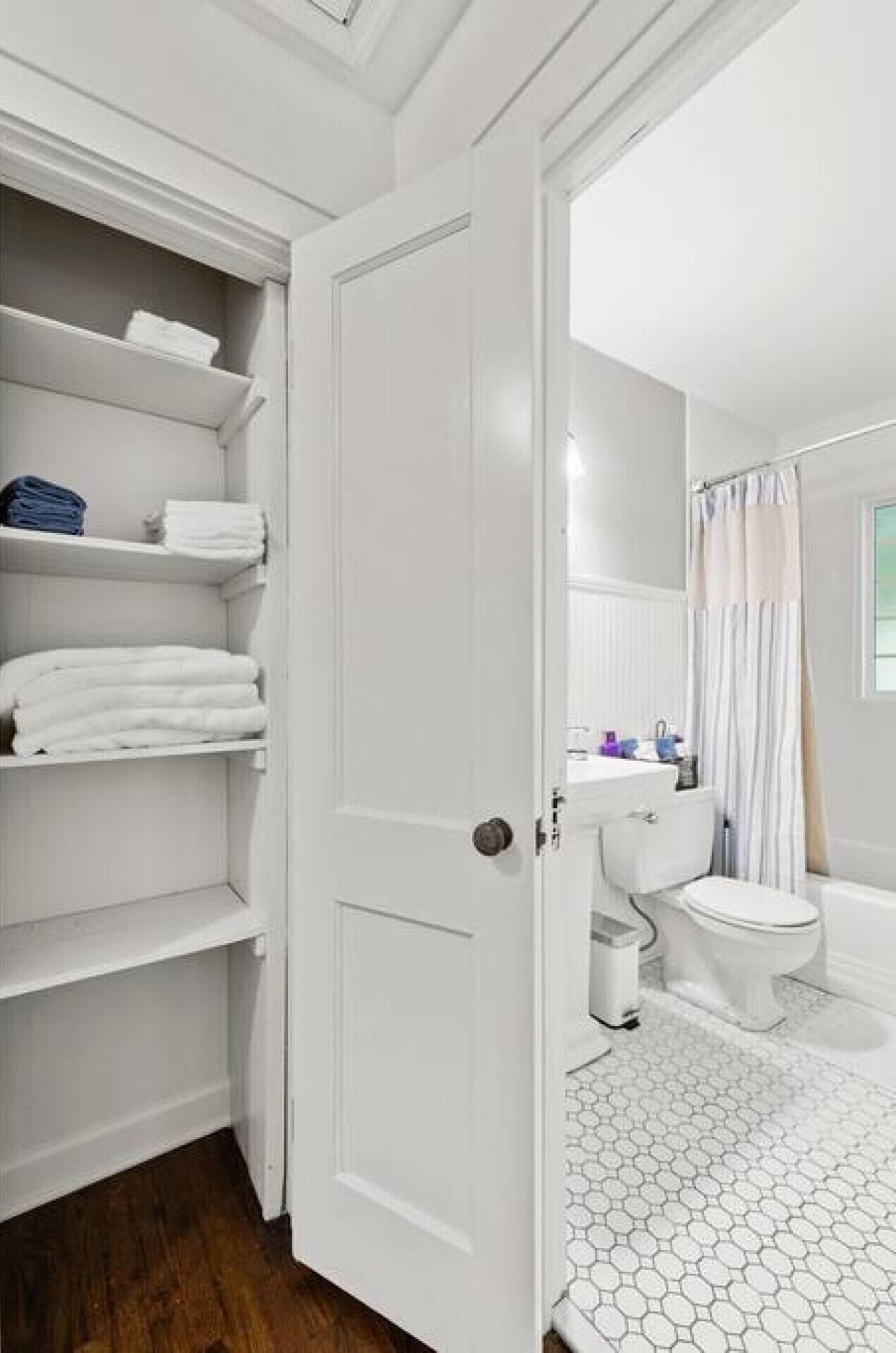 A bathroom with a white door, a toilet, a sink, and a shower area.