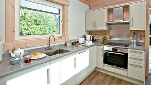 A modern kitchen with a window, stainless steel appliances, and light-colored cabinetry. - Cutterbrough, Great Field Lodges -  a lodge that sleeps 2 guests  in 1 bedroom (Braunton)