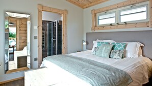 A bedroom with a bed, a window, a shower, and a view of the outside. - Cutterbrough, Great Field Lodges -  a lodge that sleeps 2 guests  in 1 bedroom (Braunton)