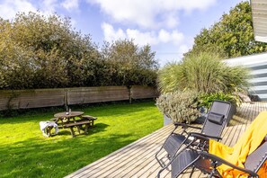 A wooden deck with outdoor furniture, a picnic table, and a wooden fence in a garden setting. - Swanpool, Great Field Lodges -  a lodge that sleeps 2 guests  in 1 bedroom (Braunton)
