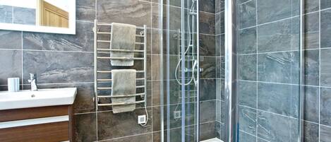 A modern bathroom with a glass-enclosed shower, a glass-enclosed bathtub, and a wooden vanity with a mirror.