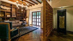 Un salon chaleureux avec un canapé, une table basse et des objets décoratifs. On y trouve une bibliothèque, un lustre et une vue par la fenêtre.