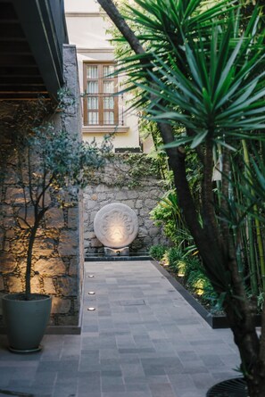 Un sendero de piedra que conduce a un edificio con una ventana y un muro de piedra decorativo.