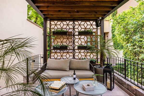 Un espace extérieur accueillant, aménagé avec un canapé, deux tables et une clôture décorative.