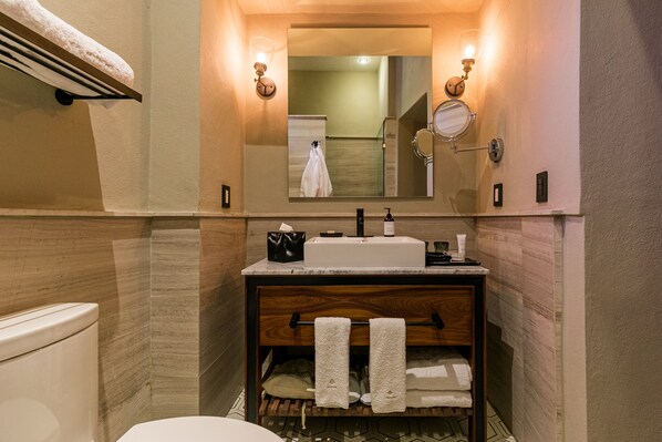 Un baño moderno con un mueble de tocador de madera, un espejo grande y un perchero para toallas.