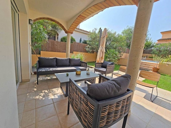 An outdoor patio with a sofa, chairs, and a table.