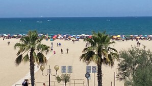 Una playa con palmeras, sombrillas y gente.