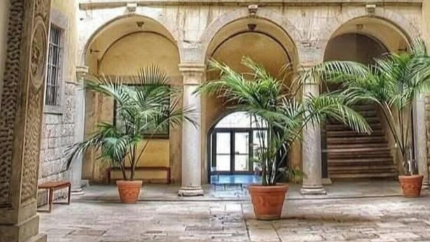 Un interior ornamentado con un balcón central, techos abovedados y columnas de estilo clásico.
