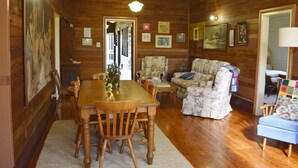 Un intérieur en bois comprenant une table à manger, des chaises, un canapé à motifs floraux et un fauteuil bleu.
