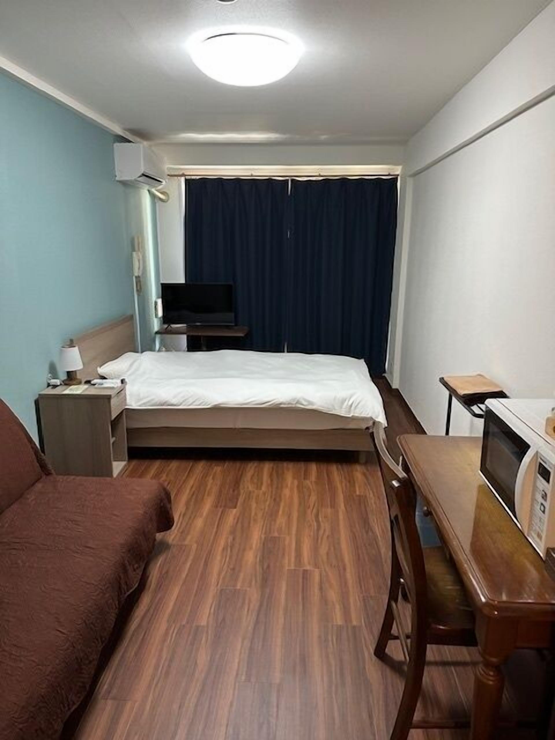 A hotel room with a bed, a desk, a chair, a television, and a microwave.