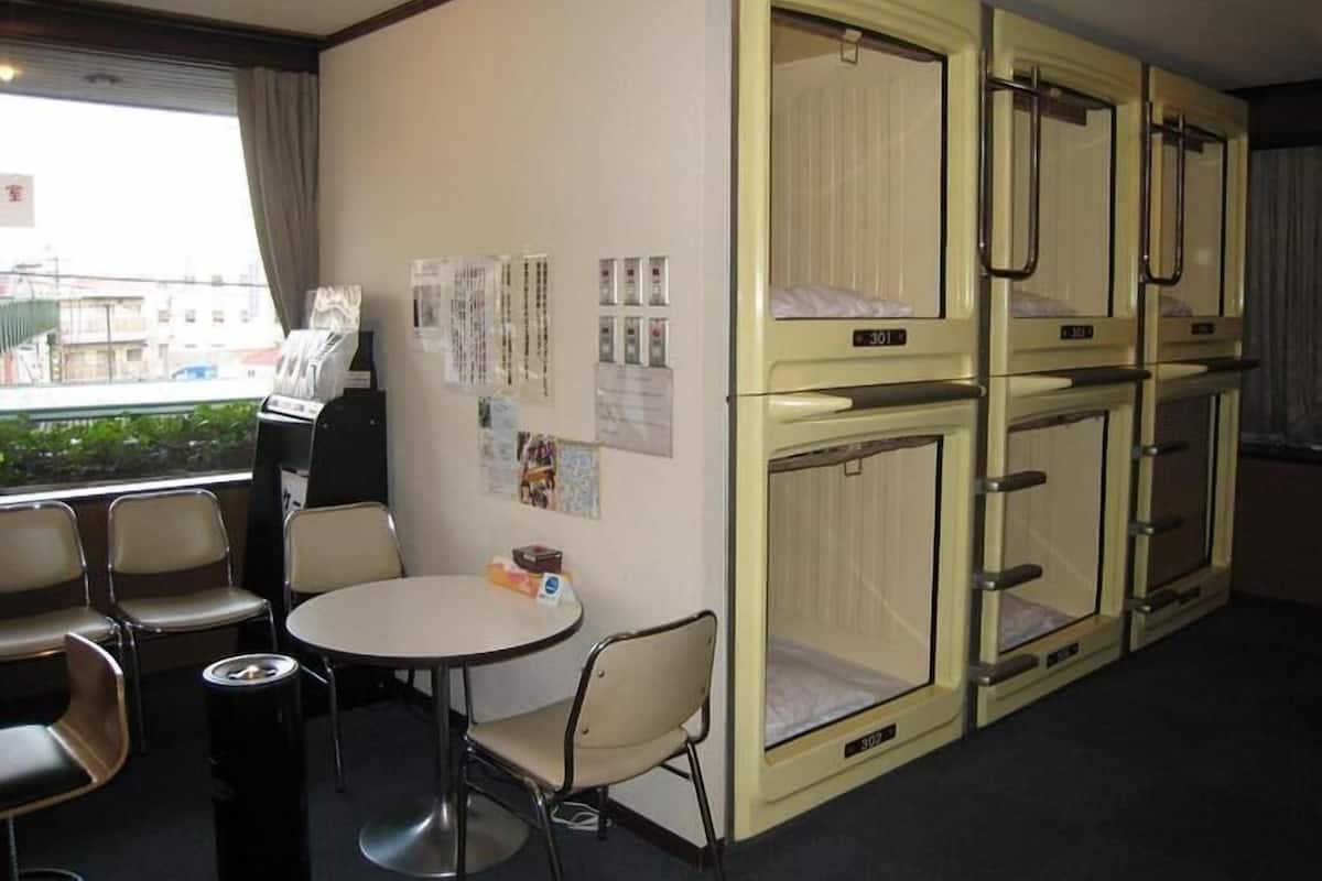 A hotel room with bunk beds, a small table with chairs, and a window with a view of buildings.