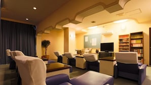 A hotel room with a seating area, a television, and a bookshelf. - Hotel Hill top (Tokyo)