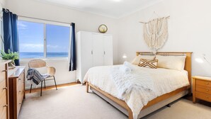 Une chambre à coucher avec un lit, un bureau, une chaise, une armoire et une vue sur la mer.