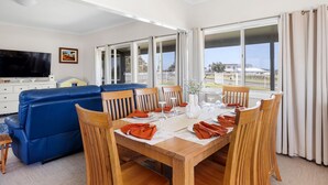 Un coin repas avec une table en bois dressée pour quatre personnes, entourée de chaises en bois.