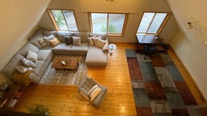 Un salon de style industriel, avec un plafond en pente, un canapé d’angle, une petite table et un tapis à motifs.