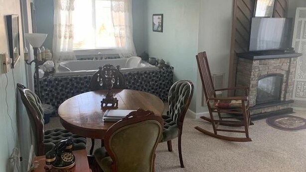 A room with a dining table, chairs, a fireplace, a bathtub, and a window with curtains. - Sugar Ski & Country Club Unit 11-803 Silver (Banner Elk)