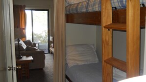 A room with a bunk bed, a sofa, and a small table. - Sugar Ski & Country Club Unit 113 Bronze (Banner Elk)