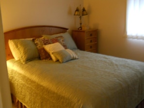 A neatly made bed with a wooden headboard, a bedside table with a lamp, and a window with curtains. - Sugar Ski & Country Club Unit 211 Bronze (Banner Elk)