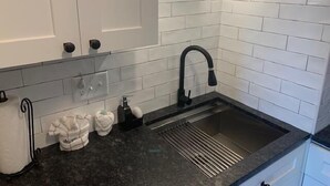 Eine moderne Küche mit weißen Ziegelsteinplatten, einem schwarzen Wasserhahn und einer Edelstahlspüle.