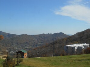 A mountain landscape with a wooden cabin, a ski lift, and buildings in the background. - Sugar Ski & Country Club Unit 411 Bronze (Banner Elk)