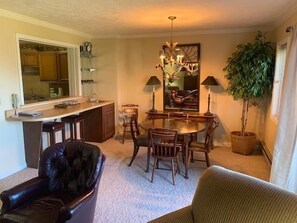 A dining area with a chandelier, wooden dining table, chairs, and a potted plant. - Sugar Ski & Country Club Unit 412 Silver (Banner Elk)