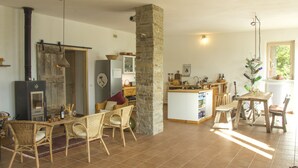 Un salón acogedor con chimenea, mobiliario de mimbre y un pilar de piedra.