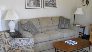 A living room with a sofa, a floral armchair, a wooden coffee table, and two framed paintings on the wall. - Sugar Ski & Country Club Unit 413 Silver (Banner Elk)