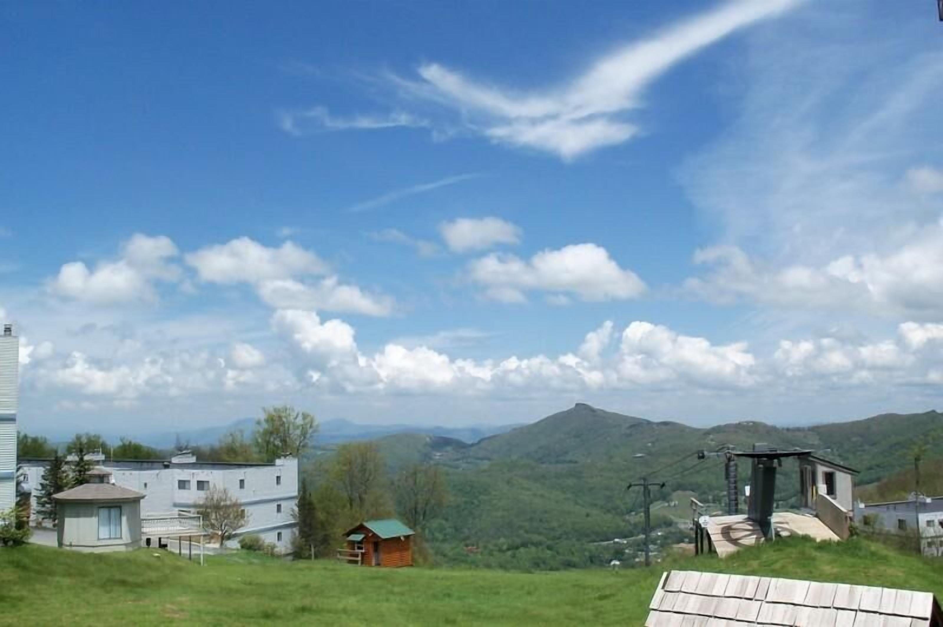 Vista de un paisaje montañoso con una cabaña pequeña y un edificio de techo plano.