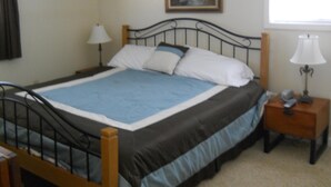 A bedroom with a bed, two bedside tables, a nightstand, a window, and a painting on the wall. - Sugar Ski & Country Club Unit 421 Bronze (Banner Elk)