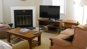 A living room with a fireplace, a television on a stand, a coffee table, and a sofa. - Sugar Ski & Country Club Unit 421 Bronze (Banner Elk)