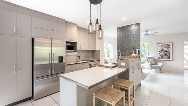 Uma cozinha moderna com eletrodomésticos de aço inoxidável, uma ilha grande com banquetas e iluminação pendente.