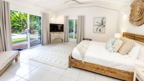Quarto com cama, televisão, ventoinha no teto e vista para o exterior.