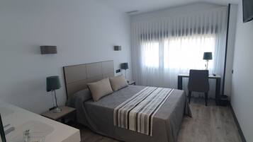 Ein modernes Hotelzimmer mit Bett, Nachttischen, Schreibtisch und Stuhl.
