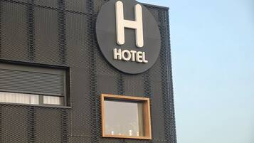 A hotel sign with a large 'H' and the word 'HOTEL' below it.