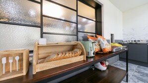 A kitchen counter with a bread basket, a toaster, and a bag of snacks. - The Way Hotel (Changwon)