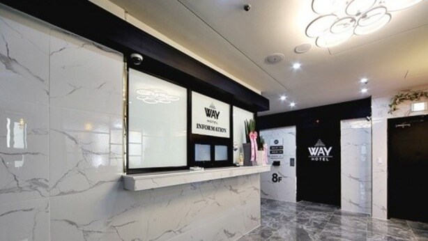 A reception area with a marble floor, a reception desk, and a sign for 'WAY HOTEL'. - The Way Hotel (Changwon)