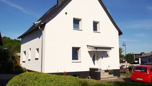 A white two-story house with a gabled roof, a chimney, and a small front porch. - Nice apartment centrally located in the Rhine-Main area (Schöneck)